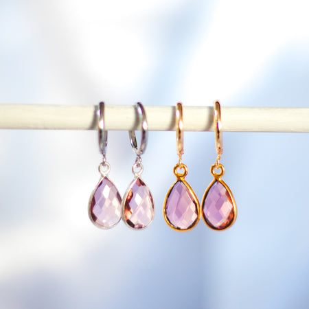 Pink teardrop earrings on a blurred background